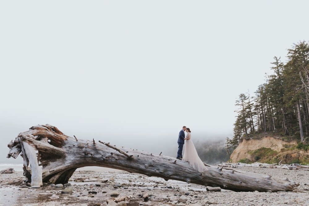 A couple stands on a fallen log along the Short Sands Beach - a great Northern Oregon Coast Elopement Location! 