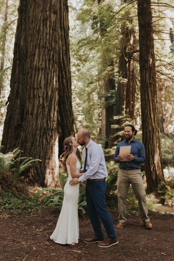 Eloping with family - a couple shares their first kiss in a Redwoods forest