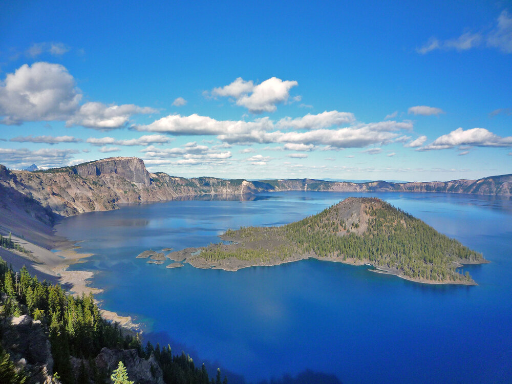 Pictured here is Crater Lake on a sunny day, with Wizard Island in the center. Photo courtesy of  National Park Service  (Public Domain)