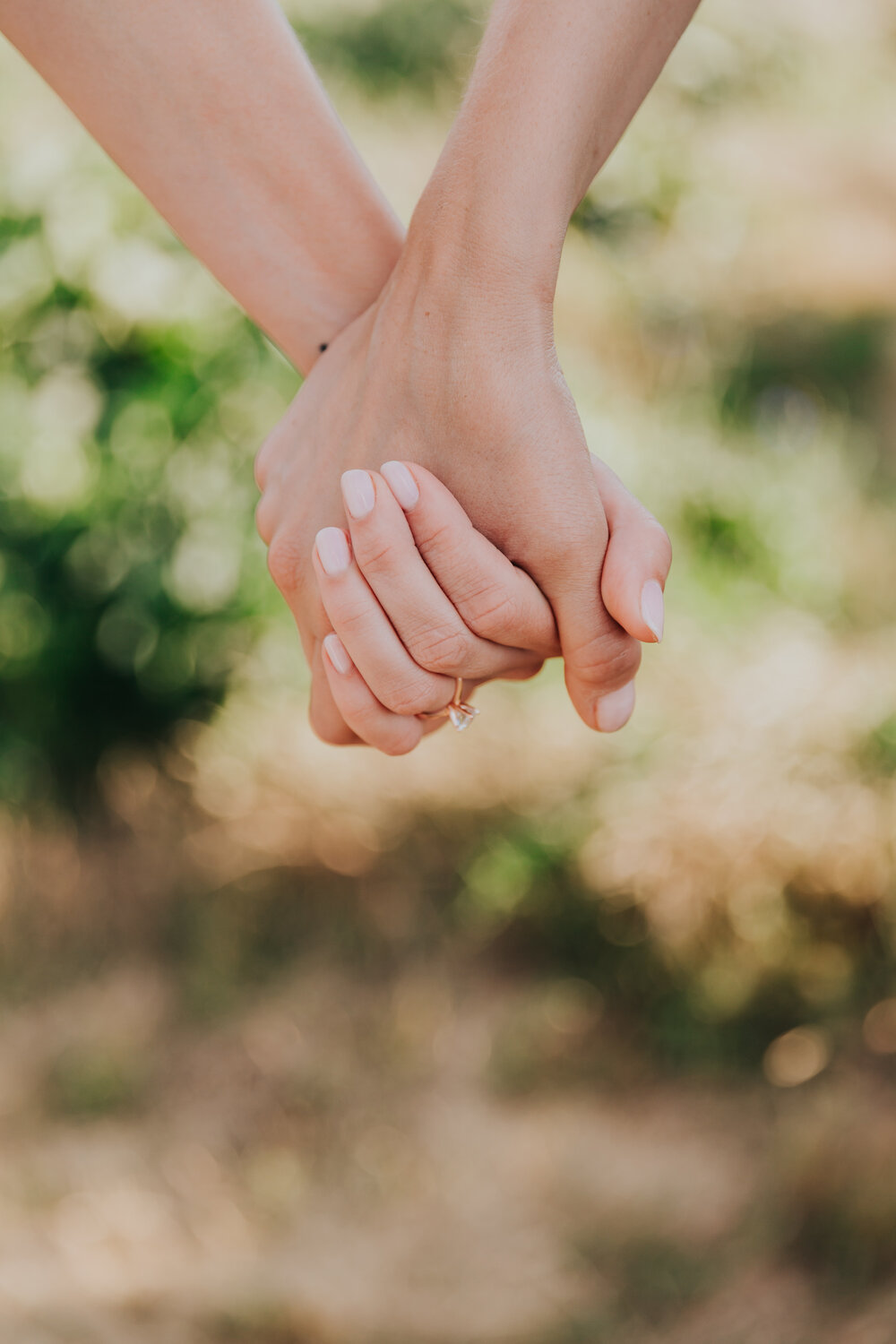 Pictured here are two people holding hands in front of a bright green background. Only the hands of the folx are visible.