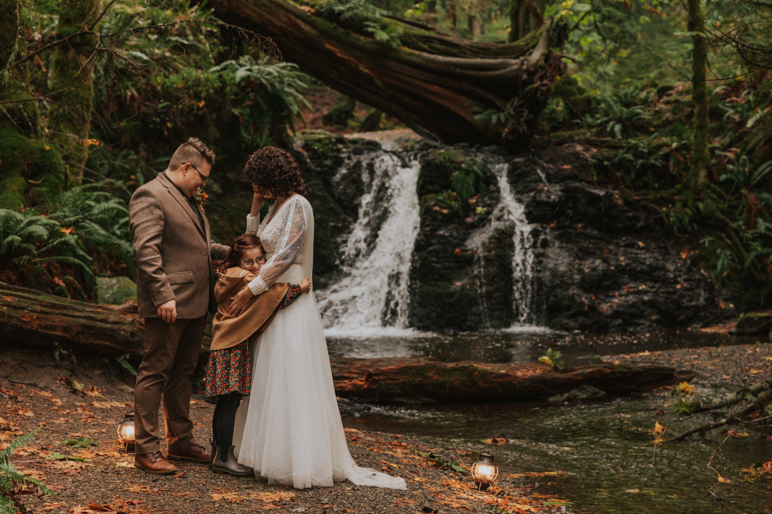 should we elope - a couple hugs their daughter in front of a waterfall on their elopement day