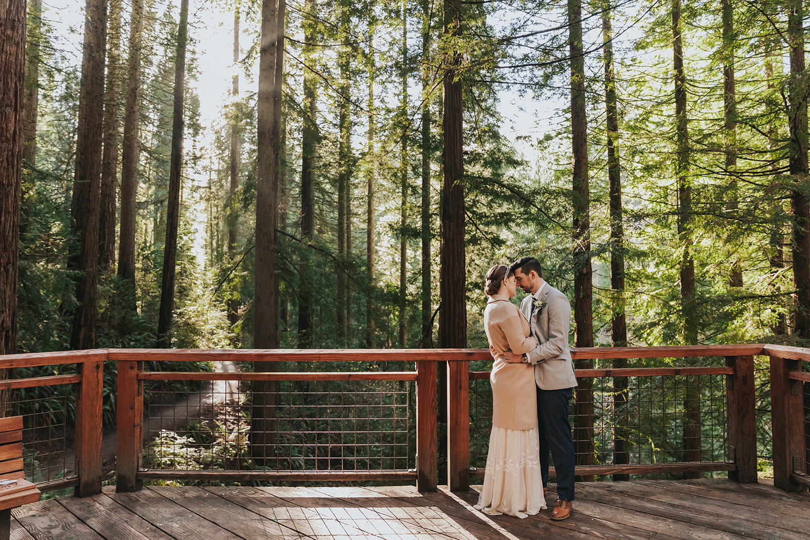 should we elope - a couple holds each other while standing on a wooden deck overlooking a forest