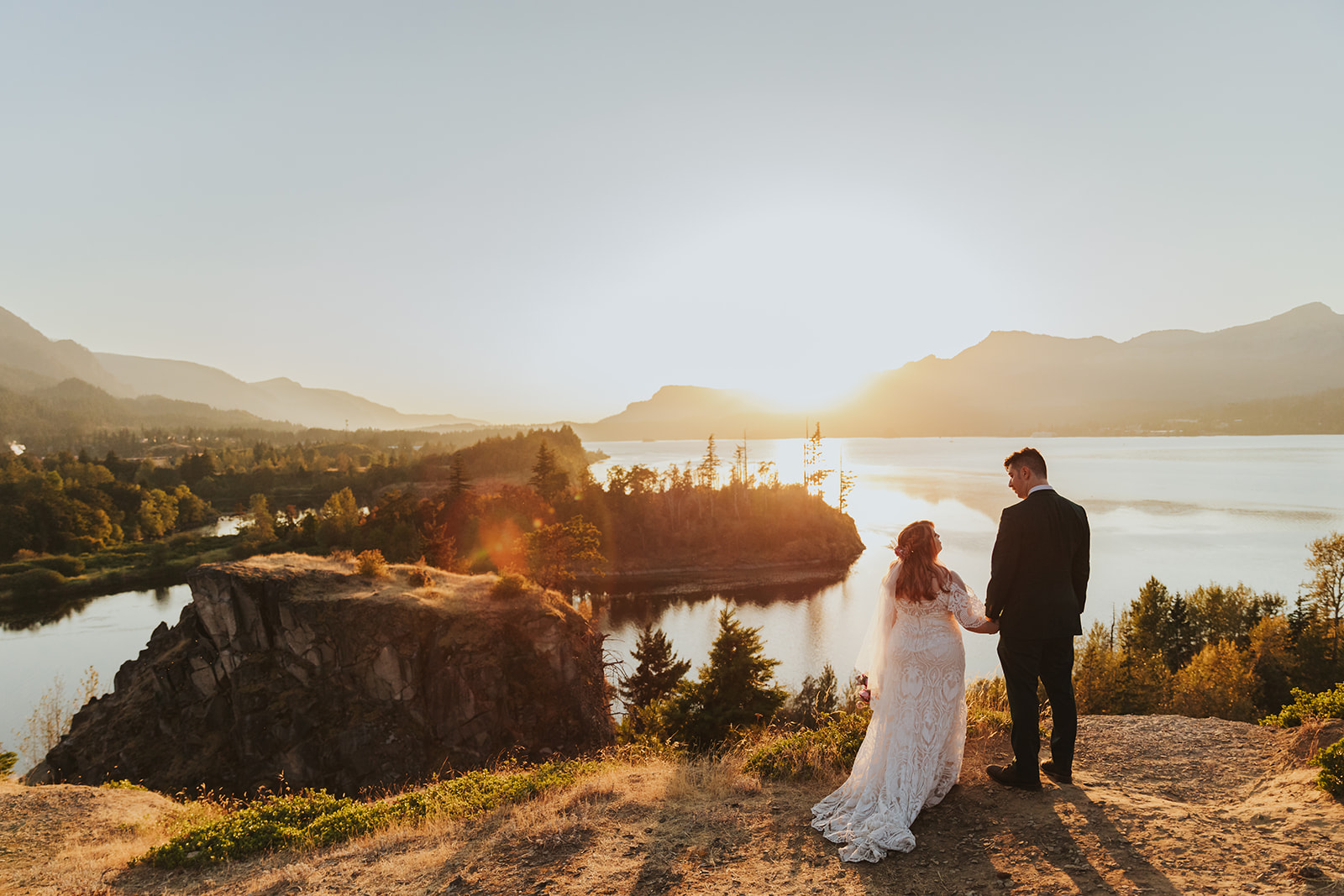 A couple holds hands during their elopement at Government Cove, overlooking the Columbia River Gorge.