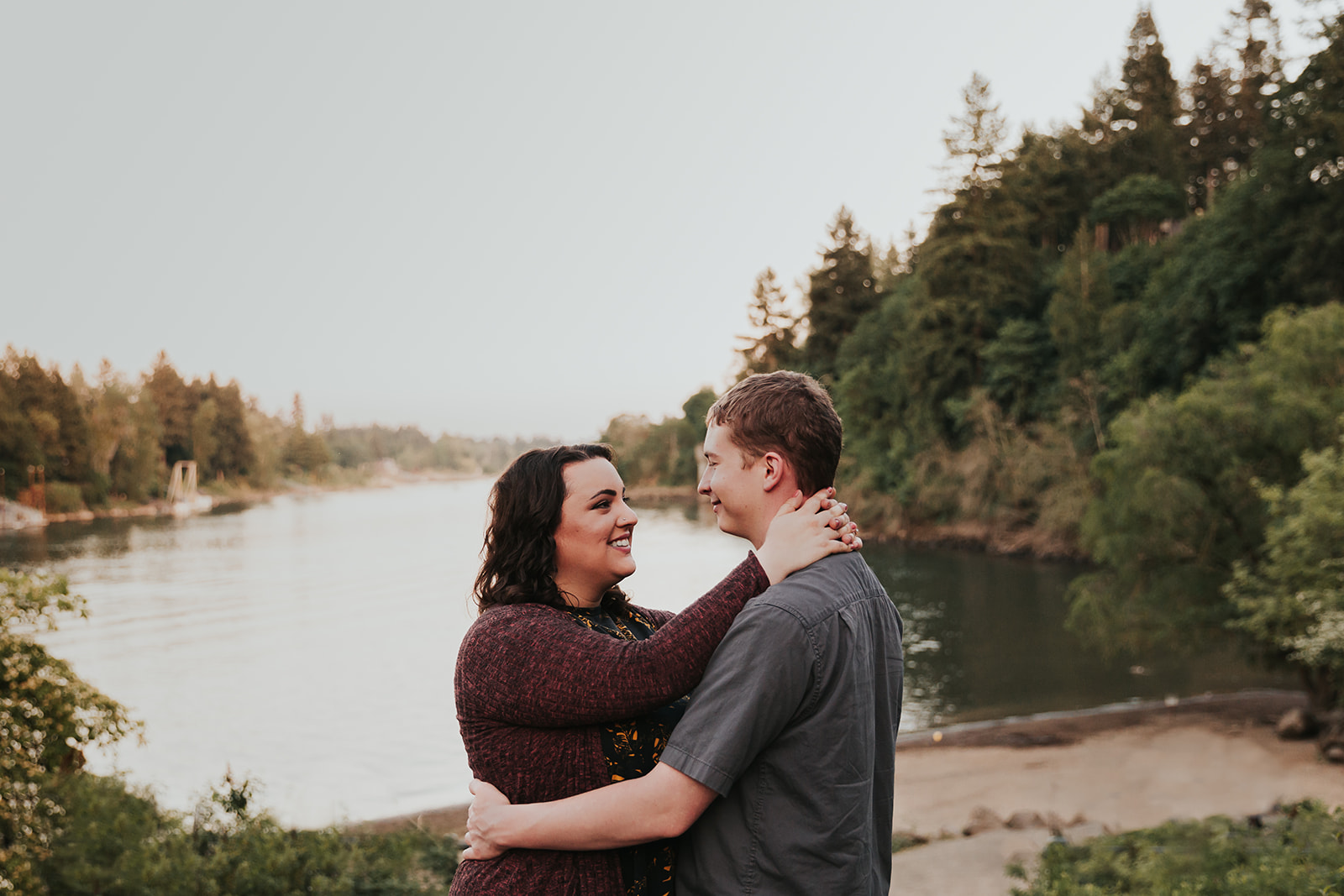 A couple smiles at each other during their engagement photo shoot at George Rogers Park, a popular Portland engagement photo location.