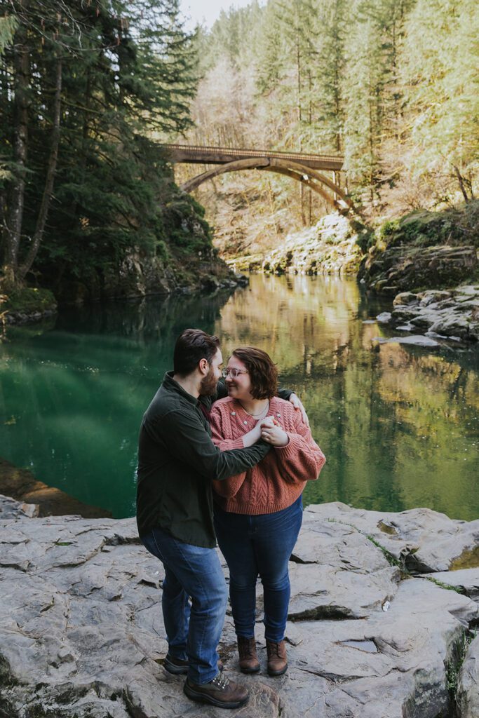 A couple kisses at Moulton Falls, a popular engagement photo location near Portland, Oregon.